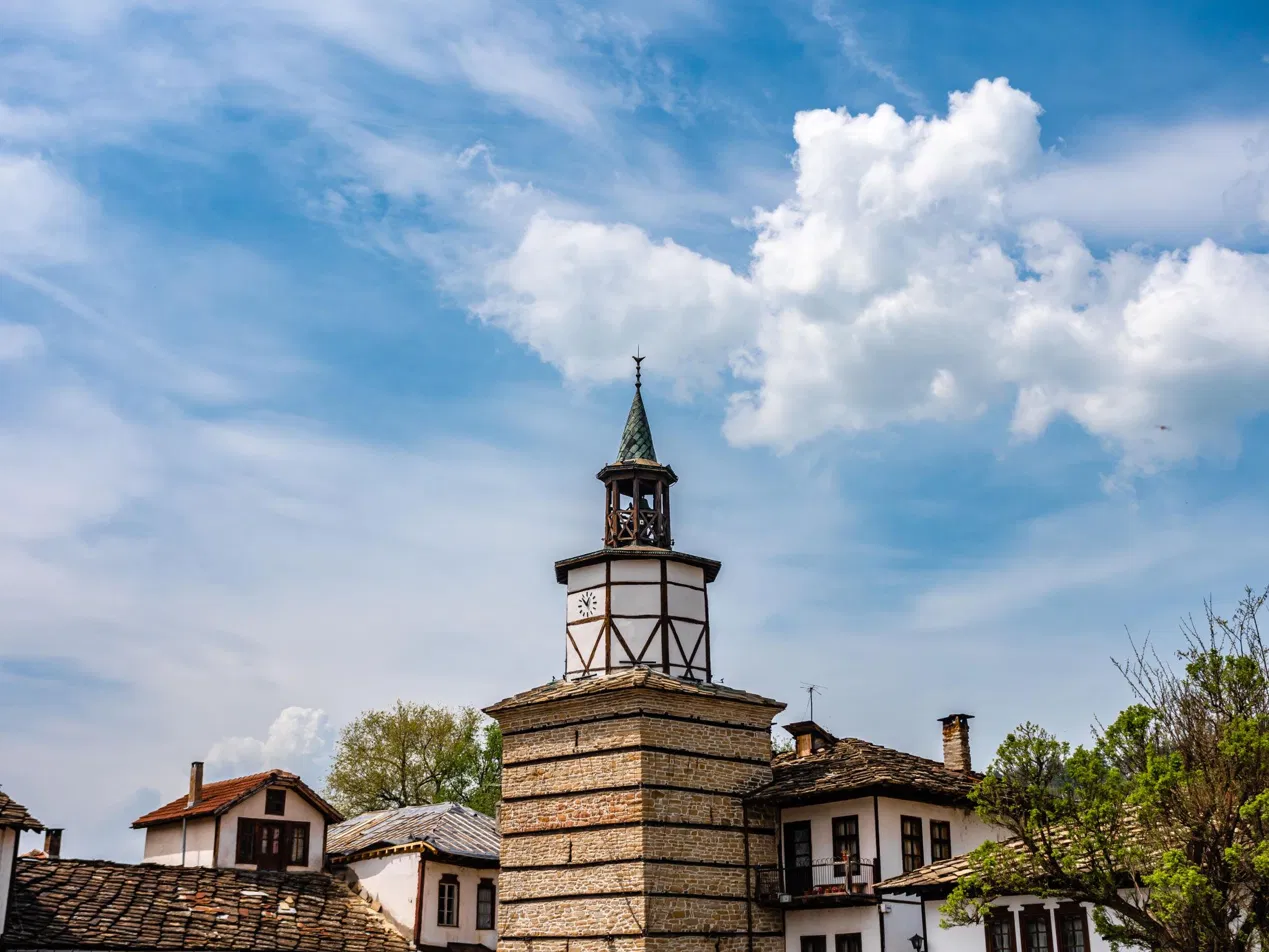 Близък кадър на часовниковата кула в Трявна под драматично синьо небе